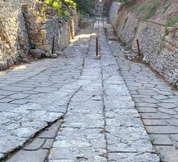 A 3,500-year-old Minoan road stretching 50 km (31 miles) from Knossos, Crete, Greece. It featured lateral drainage systems, a roadway made of 200 mm (8 inch) thick sandstone blocks bonded with a mortar of clay and gypsum. The surface was covered with basalt slabs, with separate curbs to delineate the edges of the roadway.